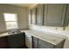 Kitchen featuring granite counters, gray cabinets, a window, and appliances at 7806 N Orleans Ave, Tampa, FL 33604