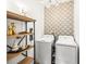 Laundry room with modern wallpaper, shelving, and front loading washer and dryer at 8460 Capstone Ranch Dr, New Port Richey, FL 34655