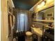 Compact bathroom featuring a pedestal sink, toilet, and shower with stylish curtain at 8502 N Branch Ave, Tampa, FL 33604