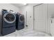 Modern laundry room with new front-loading washer and dryer with tile flooring at 9276 Ashley Dr, Weeki Wachee, FL 34613