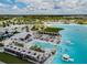 Beautiful aerial view of the community lagoon with lounge seating, a pool, a beach, and clear blue water at 9828 Branching Ship Trace, Wesley Chapel, FL 33545