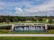 A beautifully landscaped community entrance with a water fountain and manicured lawns at 9828 Branching Ship Trace, Wesley Chapel, FL 33545