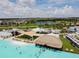 Aerial view of the community's lagoon featuring a sandy beach, tiki bar, and various lounging areas at 9828 Branching Ship Trace, Wesley Chapel, FL 33545