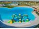 Aerial view of a community lagoon with inflatable waterpark structure and white sand beach entry at 9828 Branching Ship Trace, Wesley Chapel, FL 33545