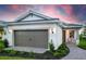 Charming home with a two-car garage, brick paved walkway and landscaped yard at dusk at 10486 Sea Breeze Ridge Dr, Englewood, FL 34223
