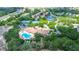 Beautiful aerial view of community featuring a clubhouse, pool, tennis courts, and scenic pond at 11121 Cherrywood Ct, Spring Hill, FL 34609