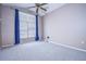 This bedroom features plush carpeting, a ceiling fan, and a large window with blue curtains at 11121 Cherrywood Ct, Spring Hill, FL 34609