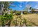 View of the backyard with lush landscaping, bright sky, and a glimpse of the sunroom entrance at 11465 7Th E St, Treasure Island, FL 33706
