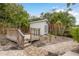 Backyard with deck and shed surrounded by tropical landscaping and brick pathway for outdoor enjoyment at 12 Bayou Ln, Palm Harbor, FL 34683