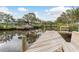 Dock view showcasing tranquil canal waters with a covered boat lift, surrounded by lush greenery at 12 Bayou Ln, Palm Harbor, FL 34683