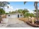Well-maintained single-story home with a two-car garage, blue front door, and lush landscaping at 12 Bayou Ln, Palm Harbor, FL 34683