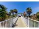 Inviting boardwalk lined with lush greenery and palm trees, leading to a serene beach and ocean view at 1200 Gulf Blvd # 1704, Clearwater Beach, FL 33767