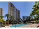 Stunning pool view with tall condos in the background, lounge chairs, palm trees, and lush landscaping under a blue sky at 1200 Gulf Blvd # 1704, Clearwater Beach, FL 33767