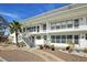 Inviting two-story condo featuring white exterior and well-maintained landscaping with a palm tree and gravel walkway at 1221 Drew St # C2, Clearwater, FL 33755
