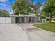 Well-kept, single-level home featuring a quaint front yard with mature trees and a covered carport at 1242 74Th N St, St Petersburg, FL 33710