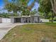 Charming single-story home with a carport, well-maintained lawn, and mature trees offering shade at 1242 74Th N St, St Petersburg, FL 33710