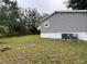 Backyard with a grassy lawn and side view of the gray house at 12426 Terra Ceia Ave, New Port Richey, FL 34654