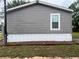 Side exterior of the gray house with a white window and green grass at 12426 Terra Ceia Ave, New Port Richey, FL 34654