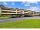 Full view of condo building with covered parking spots and lush landscaping under a partly cloudy sky at 13612 S Village Dr # 5201, Tampa, FL 33618