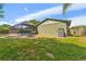 Backyard featuring a screened-in pool, lush grass, and a wood fence at 15917 Crying Wind Dr, Tampa, FL 33624