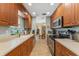 Traditional galley kitchen with wooden cabinetry, stainless steel appliances, and tiled flooring at 15917 Crying Wind Dr, Tampa, FL 33624
