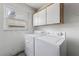 A utilitarian laundry room features a washer, dryer, window, and upper cabinets at 15917 Crying Wind Dr, Tampa, FL 33624