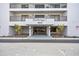 Harborage I condo building entrance featuring glass doors and professional landscaping at 1651 Sand Key Estates Ct # 54, Clearwater Beach, FL 33767