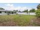 Large, private backyard with a white fence, lush green grass, and a stone fire pit at 2020 Douglas Ave, Dunedin, FL 34698