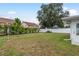 A large, fenced backyard features green grass, some palm trees, and a quaint fire pit for outdoor gatherings at 2020 Douglas Ave, Dunedin, FL 34698