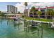 Waterfront property featuring boat lifts, lush grass, and a beautiful condo building on a sunny day at 222 Skiff Pt, Clearwater, FL 33767