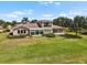 Beautiful backyard with a large, well-maintained lawn, mature trees, and a view of the house with a sunroom at 2490 Kensington Greens Dr # 0, Sun City Center, FL 33573