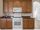 Kitchen with granite countertops, wood cabinets, white appliances, and tile flooring at 2490 Kensington Greens Dr # 0, Sun City Center, FL 33573