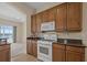 Kitchen with granite countertops, wood cabinets, white appliances, and tile floors at 2490 Kensington Greens Dr # 0, Sun City Center, FL 33573