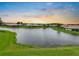 Breathtaking lake view at sunset featuring a manicured lawn and neighborhood homes at 2490 Kensington Greens Dr # 0, Sun City Center, FL 33573