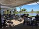 A patio with seating options overlooks a scenic lake and golf course, surrounded by palm trees and lush greenery at 2490 Kensington Greens Dr # 0, Sun City Center, FL 33573