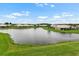 Picturesque view of a calm pond lined by manicured green lawns and beautiful homes in a serene neighborhood at 2490 Kensington Greens Dr # 0, Sun City Center, FL 33573