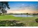 Scenic view of a tranquil pond surrounded by well-maintained lawns and community homes at sunset at 2490 Kensington Greens Dr # 0, Sun City Center, FL 33573