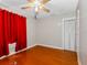 Bright bedroom featuring hardwood floors, a ceiling fan, closet, and a window with vibrant red curtains at 302 W Curtis St, Tampa, FL 33603