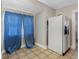 Kitchen view with tile flooring, white refrigerator, and window with blue curtains, offering a bright, functional space at 302 W Curtis St, Tampa, FL 33603