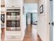 Hallway showcasing white wainscoting, wood floors, and a glimpse into the adjacent living space at 3724 Fawn Grove Ct, Land O Lakes, FL 34639