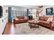 Comfortable living room featuring hardwood floors, leather sofas, and natural light from large windows at 3724 Fawn Grove Ct, Land O Lakes, FL 34639