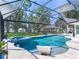 A backyard pool and spa feature a screened-in enclosure with lake views and mature trees at 3724 Fawn Grove Ct, Land O Lakes, FL 34639