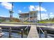 Charming waterfront home with multiple balconies, accessed by a wooden dock, surrounded by lush landscaping and clear water at 4137 Des Prez Ct, Hernando Beach, FL 34607