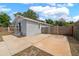 A view of the single story home with a concrete parking area, surrounded by a wooden fence at 4218 E Cayuga St, Tampa, FL 33610