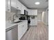 Modern kitchen featuring stainless steel appliances, white cabinets, and light wood flooring at 4218 E Cayuga St, Tampa, FL 33610