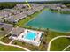 Aerial view of community pool, clubhouse, and surrounding townhomes near a lake at 4262 Cloud Hopper Way, Lutz, FL 33559