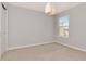 Bright bedroom with neutral walls, plush carpet, and modern light fixture at 4262 Cloud Hopper Way, Lutz, FL 33559