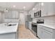 Modern kitchen with stainless steel appliances, gray cabinets, and quartz countertops at 4262 Cloud Hopper Way, Lutz, FL 33559