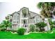 Exterior angle view of a condo building with balconies, white stairs and tropical landscaping at 5712 Biscayne Ct # 201, New Port Richey, FL 34652