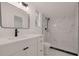 Modern bathroom featuring white marble tiling in the shower, matching vanity, black fixtures and sleek mirror at 5801 N 17Th St, Tampa, FL 33610